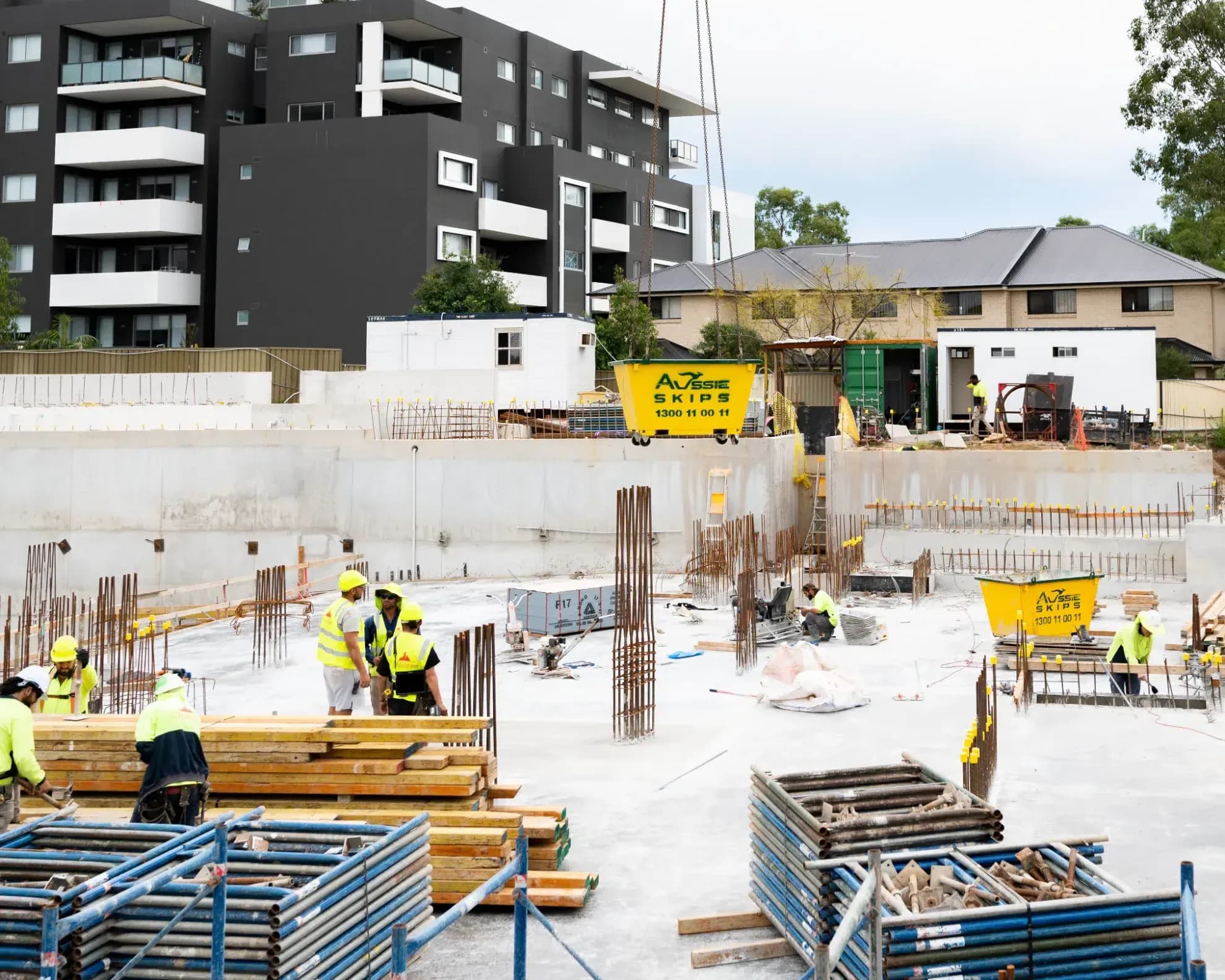Hired Aussie Skip bins being delivered to construction site with crane